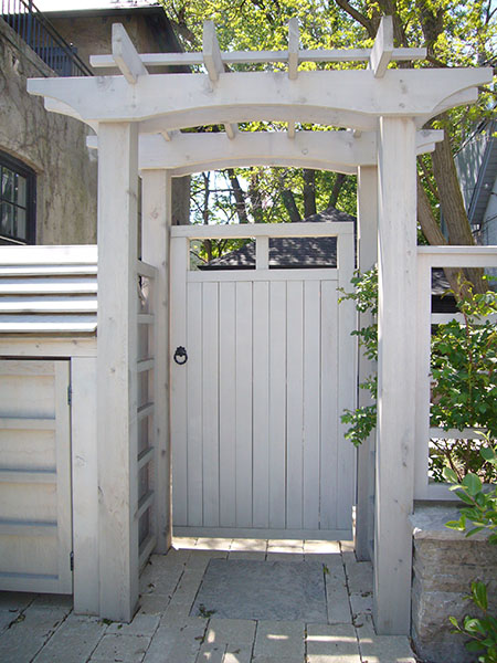 a substantial wooden gate, part of a pergola-topped arbour